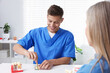 © New Africa - Doctor consulting woman regarding dental implantation at desk in clinic