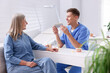 © New Africa - Doctor consulting woman regarding dental implantation at desk in clinic