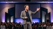 © Azorahaiá - Confident Male Speaker Gesturing While Presenting to Audience in Conference Hall with Stage Lighting