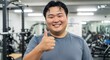 © Devina - Happy man giving thumbs up in gym workout environment.