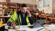 © peopleimages.com - Carpenter, writing and phone call in warehouse with laptop, timber order and stock checklist. Man, planning and contact at PC with clipboard, project management and lumber production price update