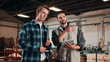 © peopleimages.com - Men, tablet and meeting in lumber workshop, carpenter and apprentice with discussion for advice in woodwork. Point, talk and supervisor with trainee, tech and team guidelines for carpentry planning