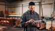 © peopleimages.com - Man, tablet and scroll in woodworking workshop, check lumber order or online inventory management. Carpenter, smile and reading on tech for digital stock analysis or search carpentry merchandise app