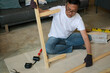 © North - senior Man furniture assembly wood frame home tool focused adult building wooden table part on floor during home improvement project