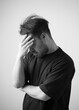 © chotiga - Man holding head in hand with pensive mood and emotion in monochrome portrait showing stress and contemplation