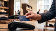 © Christine - Close-up of a customer making a contactless payment with a blue credit card at a point of sale terminal.