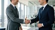 © Faisal - Two smiling businessmen shaking hands, closing a successful deal in a modern office.