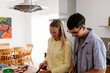 © Adrian Rodd/Stocksy - A smiling couple prepares food together at a kitchen island.
