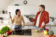 © Home-stock - Frustrated young couple arguing in kitchen, woman holding meat tenderizer