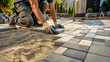 © Mitha - Professional Worker Laying Paving Blocks on Sand Foundation. Paver Installing Concrete Stone Brick Driveway Walkway. Landscaping, Patio Renovation, Hardscaping Construction Infrastructure