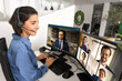 © fizkes - Customer support specialist in headset sitting at office desk, participates in multi-screen video call conference, speaks with colleagues or clients displayed on two computers monitors. Communication