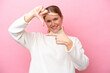 © luismolinero - Young caucasian woman isolated on pink background focusing face. Framing symbol