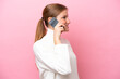 © luismolinero - Young caucasian woman isolated on pink background keeping a conversation with the mobile phone with someone