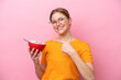 © luismolinero - Young caucasian woman holding a bowl of cereals isolated on pink background and pointing it