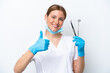 © luismolinero - Dentist caucasian woman holding tools isolated on white background with thumbs up because something good has happened