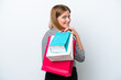© luismolinero - Young caucasian woman isolated on white background holding shopping bags and smiling