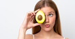 © luismolinero - Young caucasian woman isolated on white background holding an avocado. Close up portrait
