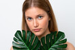 © luismolinero - Young caucasian woman isolated on white background holding a palm leaf. Close up portrait