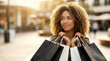 © ZaStock - Woman stands outside holding shopping bags with a smile. She is in a busy city center during sunset with shops in the background. Concept of retail, fashion, enjoyment
