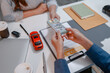 © PHOTO4U - Car purchase transaction with payment, contract signing, key handover, and customer agreement in a modern dealership office, representing automotive sales, business finance, and professional service.