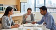 © Platon - A group of three colleagues sitting at a table in a bright office kitchen, drinking tea and reviewing notes in an open notebook during a business meeting