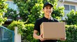 © Vadym - Smiling delivery man in uniform holds package outside house. Young courier carries cardboard box to customer door. Fast local shipping service, logistics job.