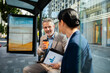 © Davor - Business colleagues chatting with coffee at city bus stop
