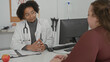 © Krakenimages.com - Man doctor wearing white coat and stethoscope points to patient's open palm across a consultation desk in a medical building; reassurance.