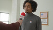 © Krakenimages.com - Man speaks into a red news microphone at a polling station, wearing an i voted sticker and answering questions about the elections; civic pride.