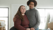 © Krakenimages.com - Plus size woman holding keys and hugging man inside a building entry with moving boxes and rolled rug visible; new home joy.