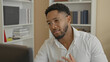 © Krakenimages.com - Man at computer wearing glasses and white shirt gestures with hand while studying the monitor, beard visible, bookshelf and plant in office; concentration problem solving.