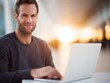 © Road Red Runner - A man smiles while typing on a laptop in a bright modern environment as he sets boundaries for work-life balance