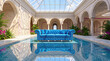 © Celt Studio - Luxurious bright blue tufted sofa floating inside shallow indoor pool featuring elegant classical architecture beautiful tropical plants clear skylight roof bright summer sunshine