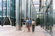 © pablo - Diverse business professionals walking and discussing work while holding a tablet in a modern city setting