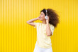 © VISTA by Westend61 - Woman listening to music with headphone on vibrant yellow background