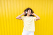 © VISTA by Westend61 - Smiling woman enjoying music with headphone on yellow background