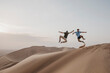 © TrueShot | Westend61 - Namibia, Namib, two friends jumping in the air on desert dune