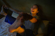© TrueShot | Westend61 - Smiling woman playfully stretching on bed at twilight