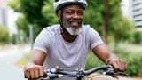 Man riding bicycle on a tree-lined path in an urban setting, wearing a helmet and smiling, with modern buildings visible in the background
