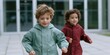 © Iryna - Two young boys running outdoors in lightweight jackets on a paved plaza for kids lifestyle background and activity banner