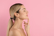 © Anastasiya - Young beautiful woman in side profile touching her chin with eyes closed, posing on pink studio background for skincare, facial care and beauty concepts, copy space