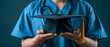 © Olga Ко - Close-up of an unrecognizable medical student in blue scrubs with a stethoscope holding a black graduation cap. Medical education and healthcare career concept