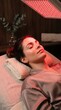 © Darya - Woman relaxing during red light therapy session at spa. Patient receiving facial rejuvenation treatment with infrared LED panel device. Wellness, skincare and healthy lifestyle concept.