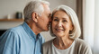 © SYATRI RAWU - Happy Senior Couple Sharing a Secret Indoors; Loving Elderly Man Whispering into His Smiling Wife's Ear while At Home Together during Retirement
