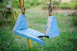 © Ichsan Gallery - Broken plastic children's swing on the playground, old and unsafe swing. Old blue swing in an abandoned outdoor playground rustic environment