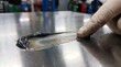 © Zishan - Applying dark industrial lubricant on a polished metal surface in a professional workshop setting