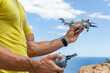 © ADDICTIVE STOCK - Man holding drone and remote controller by sea cliff