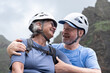 © luciano - Senior couple enjoying active outdoor lifestyle, wearing helmets and smiling while hugging during a mountain hike, representing love, adventure, and togetherness
