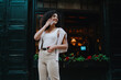 © BullRun - Smiling young Hispanic woman checking transport schedule or travel route on smartphone on cozy city street, modern youth navigation, lifestyle and digital connectivity concept