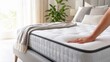 © xuxu - A close-up of a woman's hand testing the softness and comfort of a new mattress featuring a relief pattern and a textured surface.